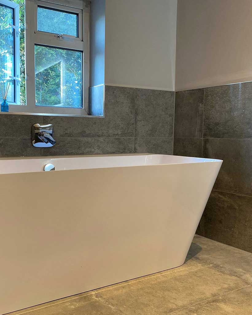 Freestanding bath against grey tiles