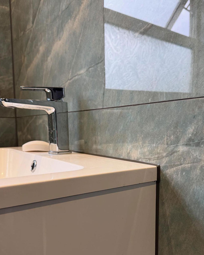 Colour-matched joint where a basin meets marble-effect tiles